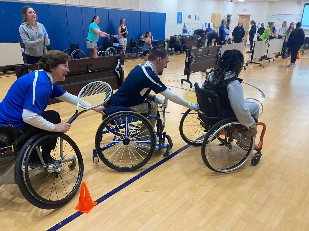 A wheelchair-based recreational therapy exercise is being performed in a gym